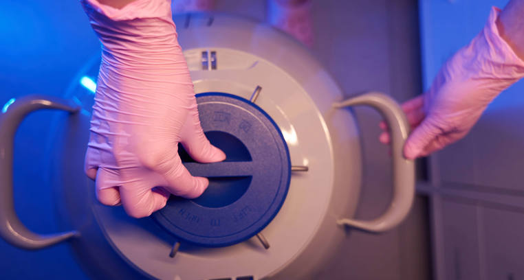 IVF laboratory scientist using a cryogenic container – showcasing Noblegen liquid nitrogen generator applications in fertility treatment and embryo preservation